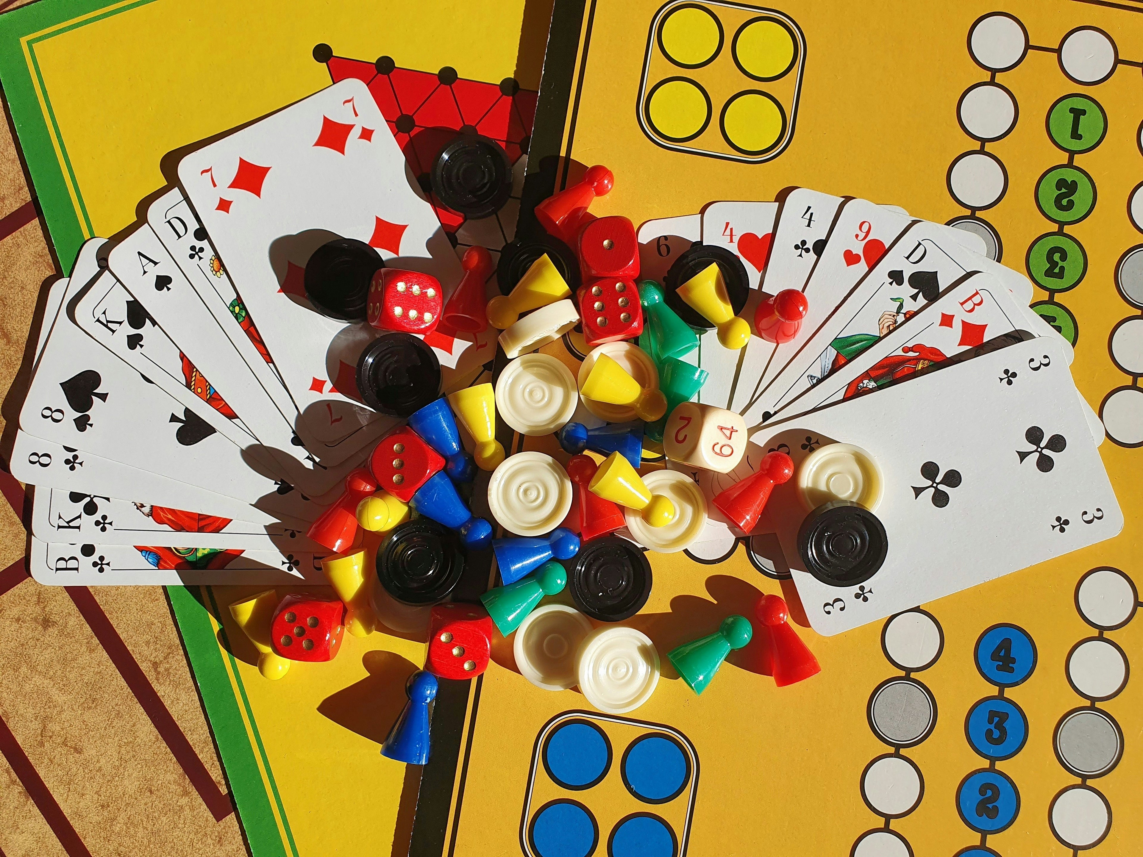 Playing cards and colorful game pieces on a yellow board with game elements.
